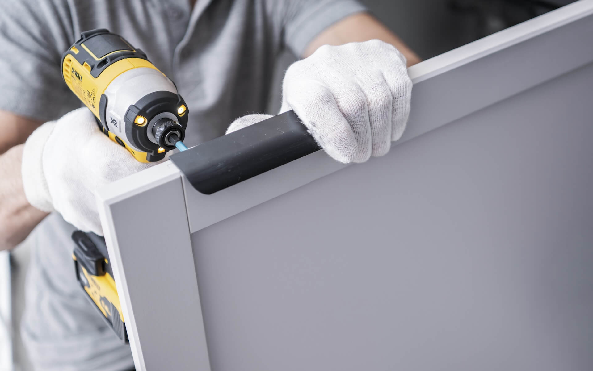 Närbild på montering av ett handtag med en skruvdragare, ett effektivt moment under en köksrenovering.