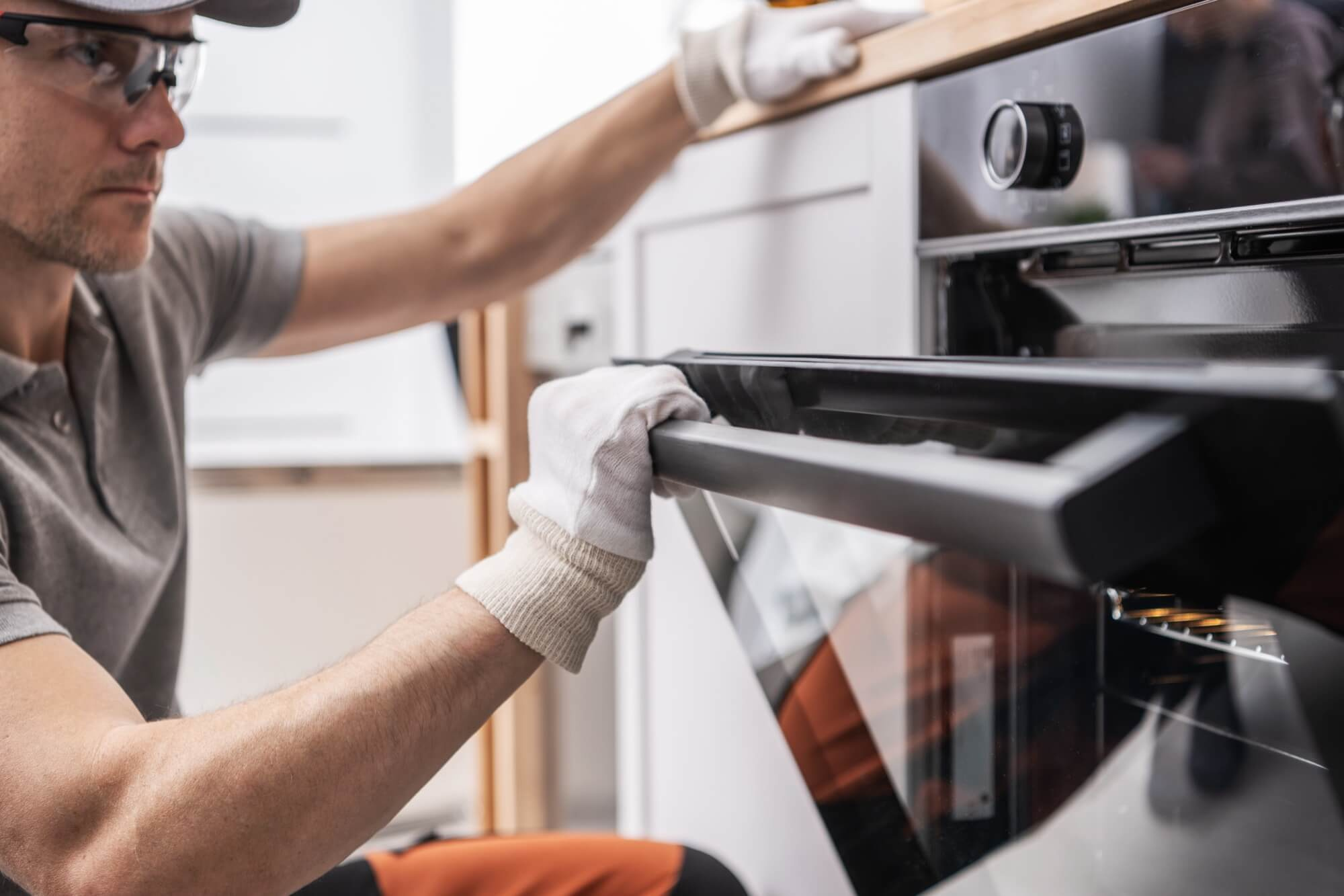 En tekniker installerar en inbyggnadsugn, en vanlig del av en omfattande köksrenovering.