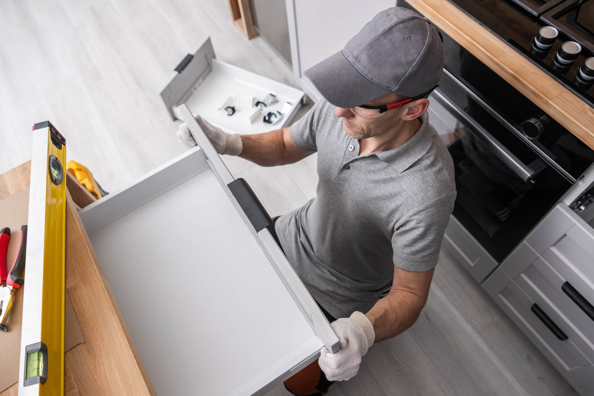 En montör kontrollerar noggrant inpassningen av en kökslåda, vilket visar precisionen i en professionell köksrenovering.