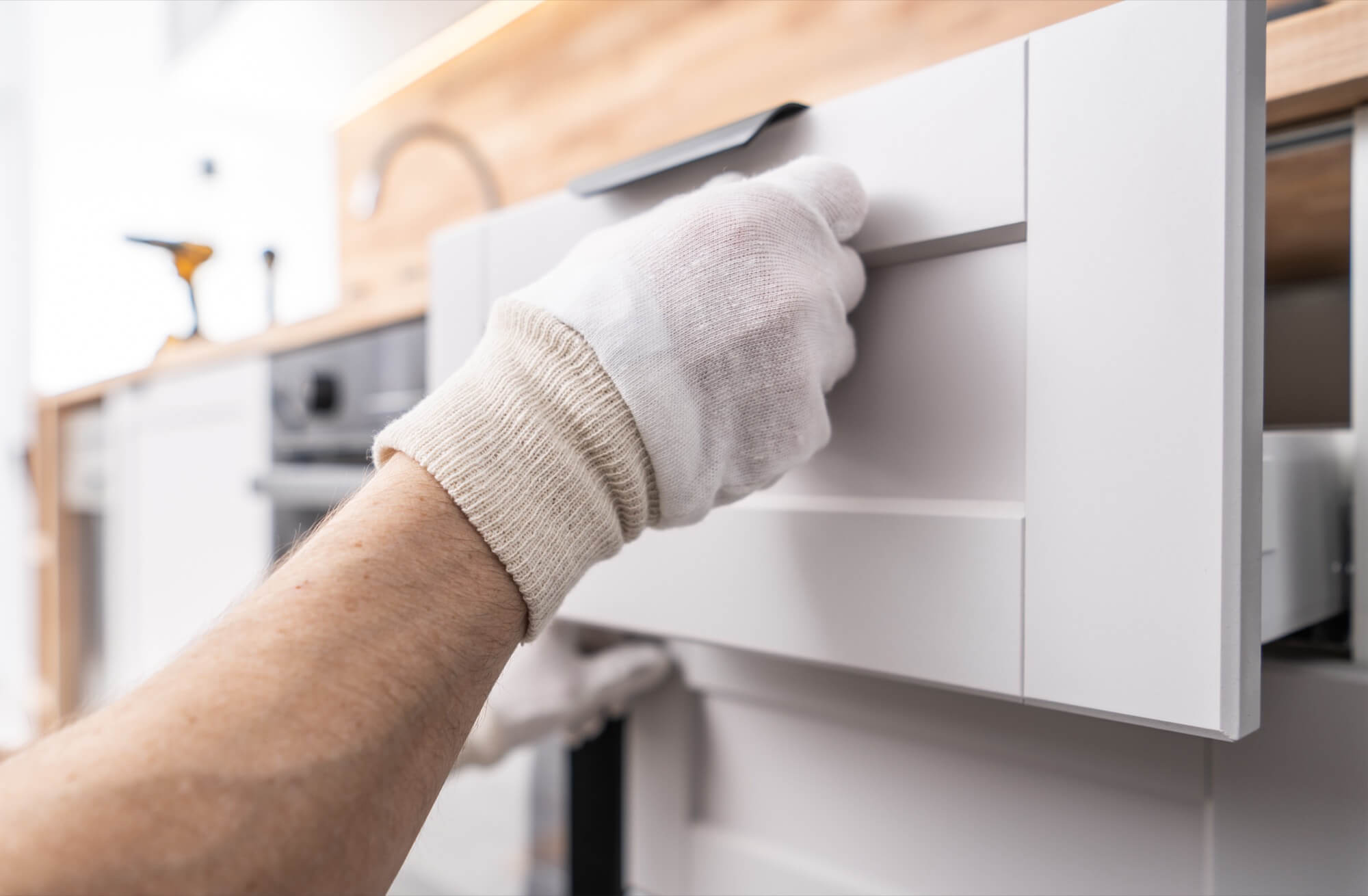 En hantverkare kontrollerar funktionen på en nyinstallerad kökslåda efter en lyckad köksrenovering.