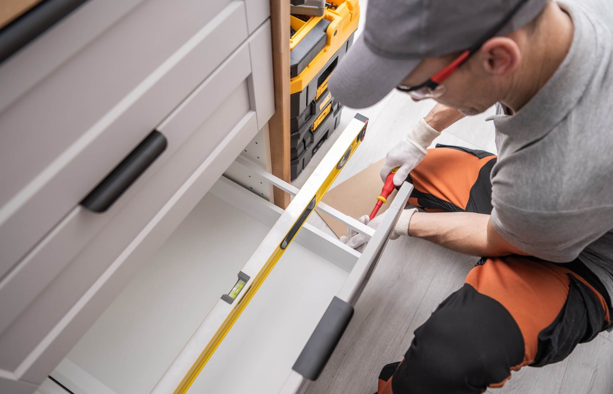 En hantverkare använder ett vattenpass för att säkerställa att kökslådan är perfekt installerad under en köksrenovering.
