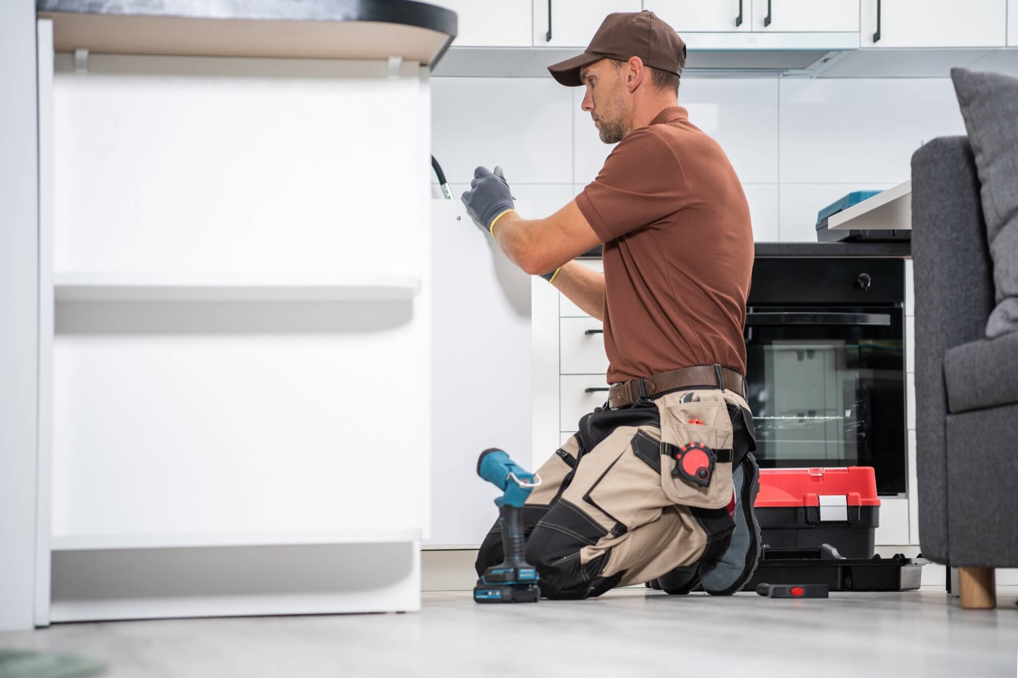 En snickare på knä som monterar köksinredning, vilket visar hantverket bakom en köksrenovering.