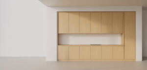 Fotorealistisk bild av ett specialbyggt köksskåp i ljust trä mot en vit vägg. Skåpet är en del av den minimalistiska designen.