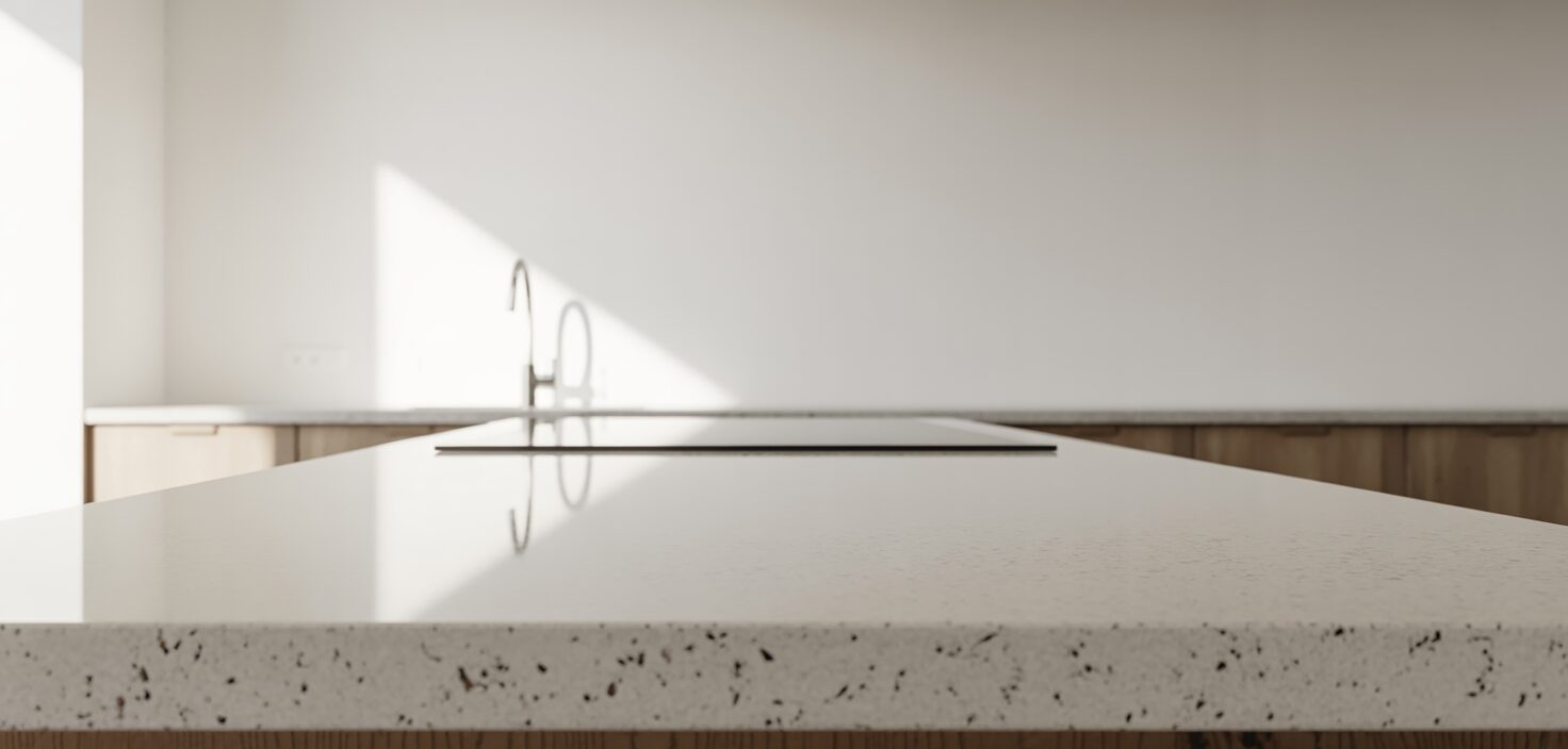 Närbild av en minimalistisk vit kompositbänkskiva i ett kök med rent ljus och fokus på detaljer.